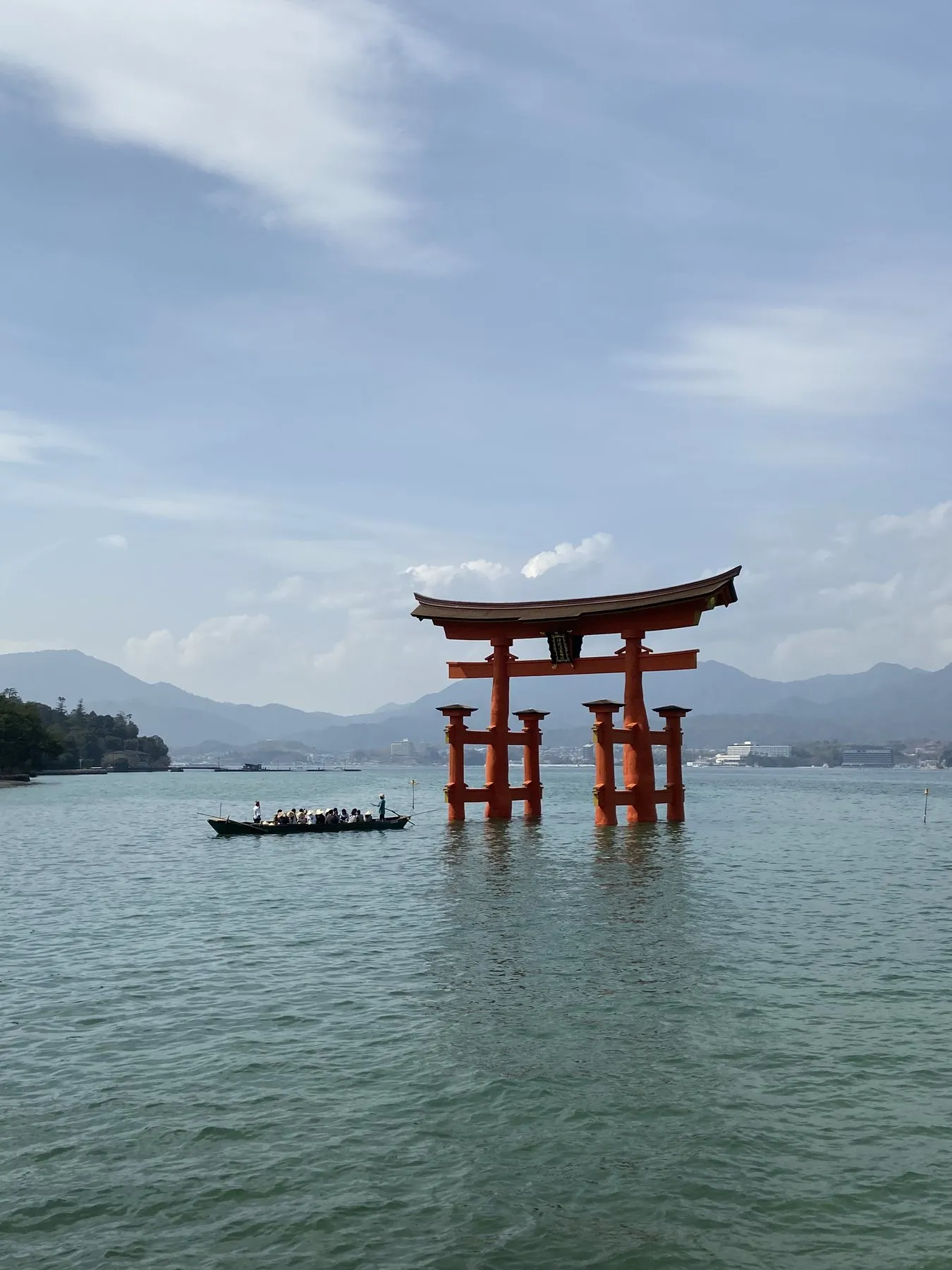 The great torii of Itsukushima Shrine rising from the sea at Miyajima, a small rowboat passing by