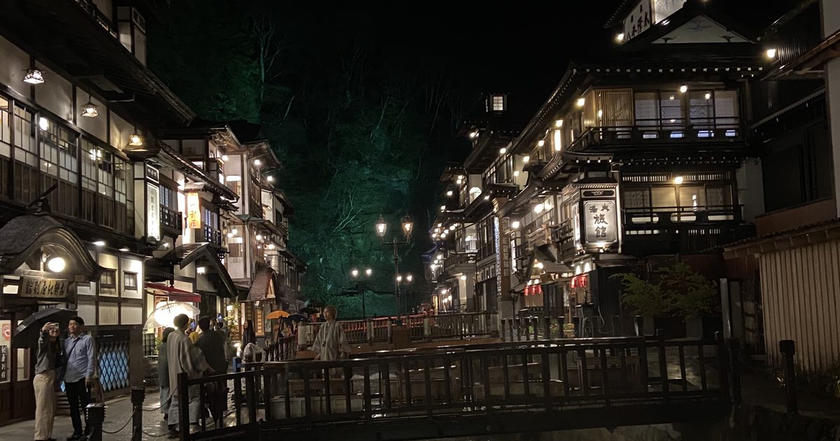 Ginzan Onsen's riverside street at night, wooden ryokan lit up on both sides